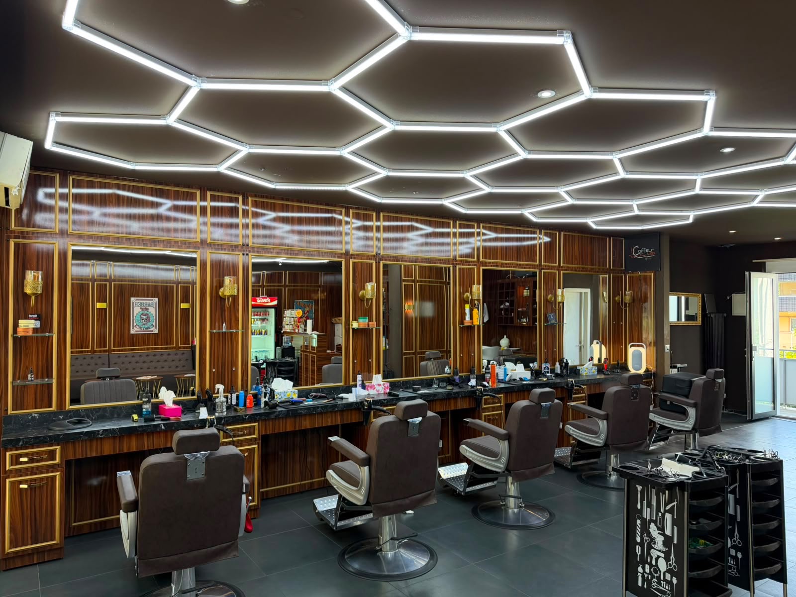 Salon Coiffeur Leo mit Holzfronten, Goldrahmen, Spiegeln und Barberstühlen